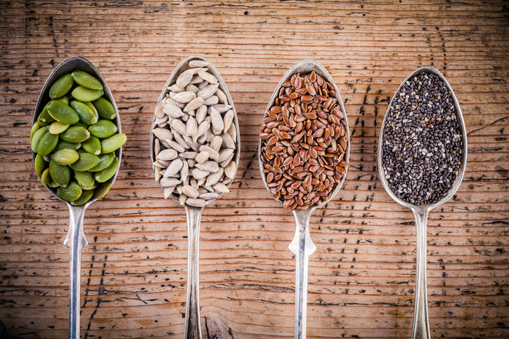 Chia, sunflower, pumpkin and sesame seeds in wooden spoons